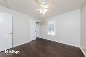 Lewisville house for rent - a bedroom with white walls and a ceiling fan and wood floors