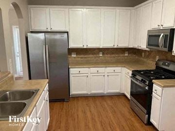 Cartersville house for rent - A kitchen with white cabinets and a stainless steel refrigerator.