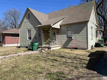 Gainesville house for rent - A house with a grey roof and a green trash can in front.