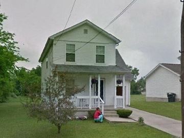 Warren house for rent - A man sits on the front porch of a two-story house.