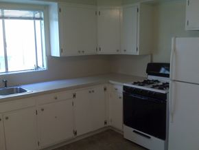 Oakland apartment for rent - an empty kitchen with white cabinets and a stove and refrigerator