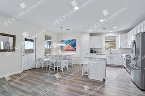 Hutto house for rent - A modern kitchen with white cabinets and a wooden floor.