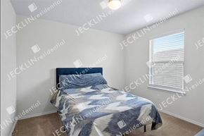 Hutto house for rent - A bedroom with a bed and a window with blinds.