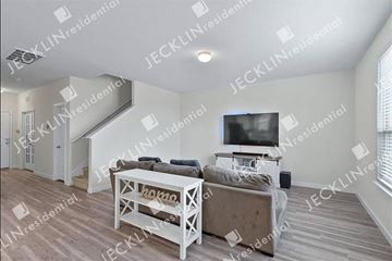 Hutto house for rent - A living room with a white couch and a television on the wall.