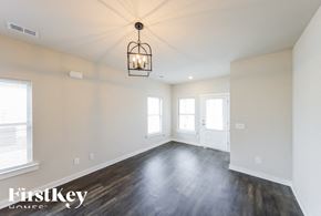 Cullman house for rent - A large empty room with wooden floors and a hanging light fixture.