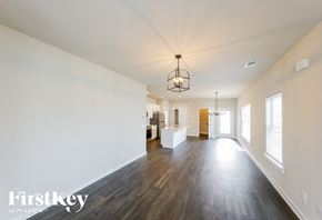 Cullman house for rent - A large empty room with wooden floors and a chandelier hanging from the ceiling.