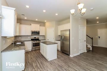 Dallas house for rent - a kitchen with white cabinets and a stainless steel refrigerator