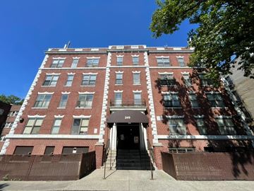 East Orange apartment for rent - A red brick building with a black awning and a set of stairs leading up to the entrance.