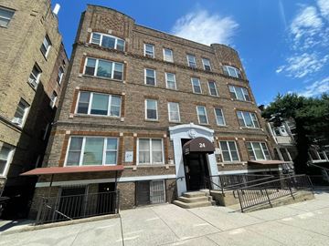 East Orange apartment for rent - A brown brick building with a red awning and a black gate in front.