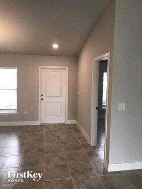 Fort Myers house for rent - an empty room with a white door and tiled floor