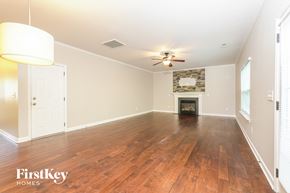 Kernersville house for rent - A spacious room with wooden floors and a fireplace.