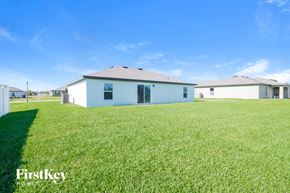 Leesburg house for rent - A white house with a grey roof is surrounded by a grassy field.