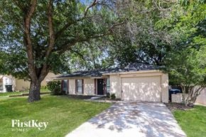 Garland house for rent - A house with a garage is surrounded by trees and has a driveway leading to the front door.
