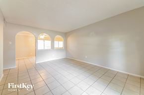 Garland house for rent - A spacious room with white walls and tile flooring, featuring three arched windows.