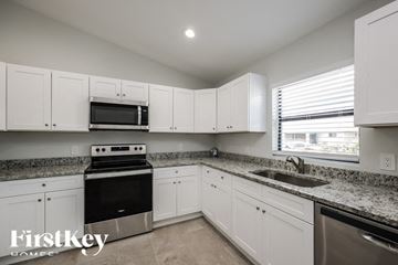 Lehigh Acres house for rent - a kitchen with granite counter tops and white cabinets