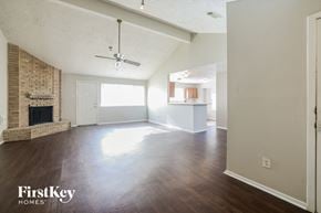 Houston house for rent - an empty living room with a fireplace and wood flooring