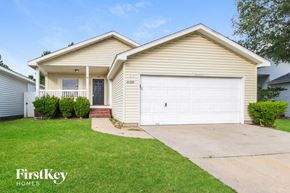 Tomball house for rent - A beige house with a white garage door and a black door.