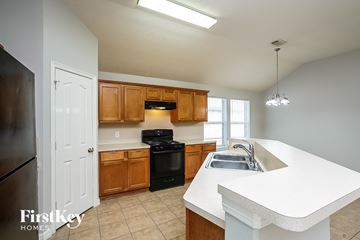 Spring house for rent - A kitchen with a white counter top and wooden cabinets.