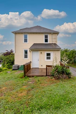 Rosedale apartment for rent - A house with a white door and windows is surrounded by greenery.
