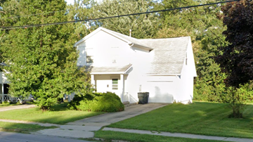 Warren house for rent - A white building with a garage door is surrounded by greenery.