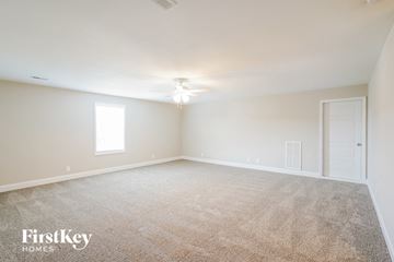 Clarksville house for rent - a spacious living room with carpet and a ceiling fan