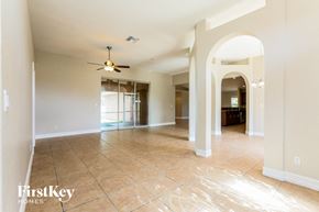 Lehigh Acres house for rent - an empty living room with a ceiling fan and tiled floors