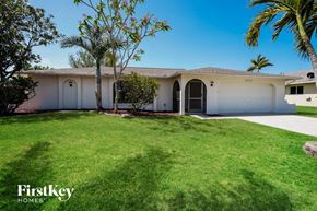 Cape Coral house for rent - a white house with a lawn and palm trees