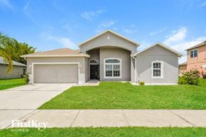 Kissimmee house for rent - a beige house with a lawn in front of it