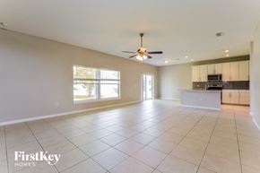 Kissimmee house for rent - an empty living room and kitchen with a ceiling fan