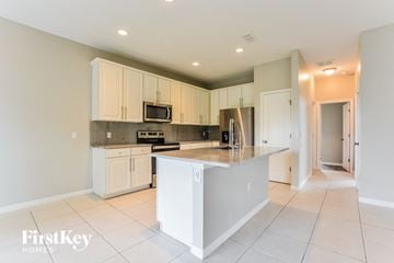 Kissimmee house for rent - a large kitchen with white cabinets and a counter top