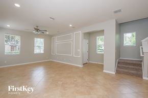 Riverview house for rent - A spacious room with a fan and a staircase leading to another room.