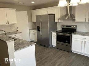 Lochbuie house for rent - a kitchen with stainless steel appliances and white cabinets