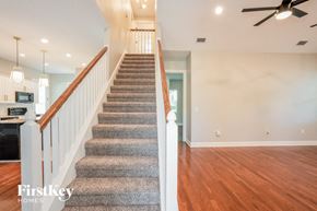 Plant City house for rent - a carpeted staircase in a home with a hard wood floor and a ceiling fan
