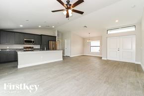 Lehigh Acres house for rent - an empty kitchen and living room with a ceiling fan