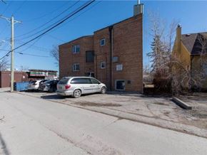 Winnipeg apartment for rent - A grey van is parked in front of a brick building.