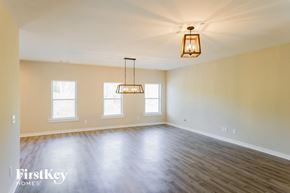 Parrish house for rent - A large empty room with wooden floors and a hanging light fixture.