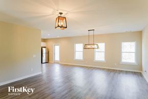 Parrish house for rent - A spacious room with wooden floors and a hanging light fixture.