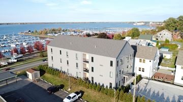 Erie apartment for rent - A large white building with a grey roof is surrounded by a parking lot and other buildings.