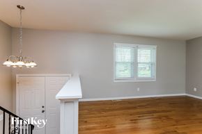 Maryland Heights house for rent - a living room with a staircase and a window and a wood floor