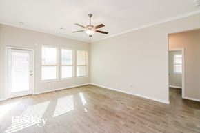 Conroe house for rent - A spacious room with a ceiling fan and wooden flooring.