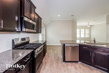 Conroe house for rent - A kitchen with dark brown cabinets and a granite countertop.