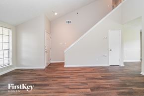 Houston house for rent - A spacious room with wooden flooring and a staircase leading to another level.