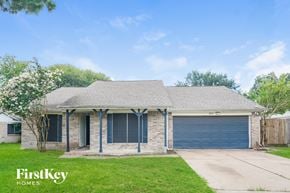 Houston house for rent - A house with a garage door and a tree in front of it.