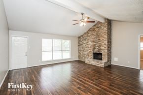 Houston house for rent - A room with a stone fireplace and wooden floors.