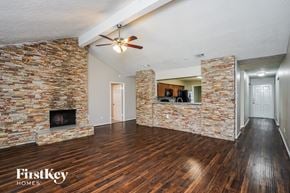 Houston house for rent - A room with a stone fireplace and wooden floors.
