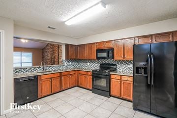 Houston house for rent - A kitchen with wooden cabinets and a black refrigerator.