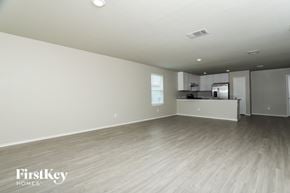 San Antonio house for rent - A spacious empty room with wooden flooring and a kitchen area in the background.