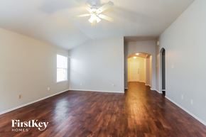 Humble house for rent - an empty living room with wood flooring and a ceiling fan