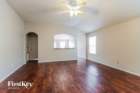 Humble house for rent - an empty living room with wood flooring and a ceiling fan