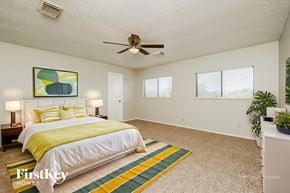 San Antonio house for rent - A bedroom with a bed, a ceiling fan, and a painting on the wall.